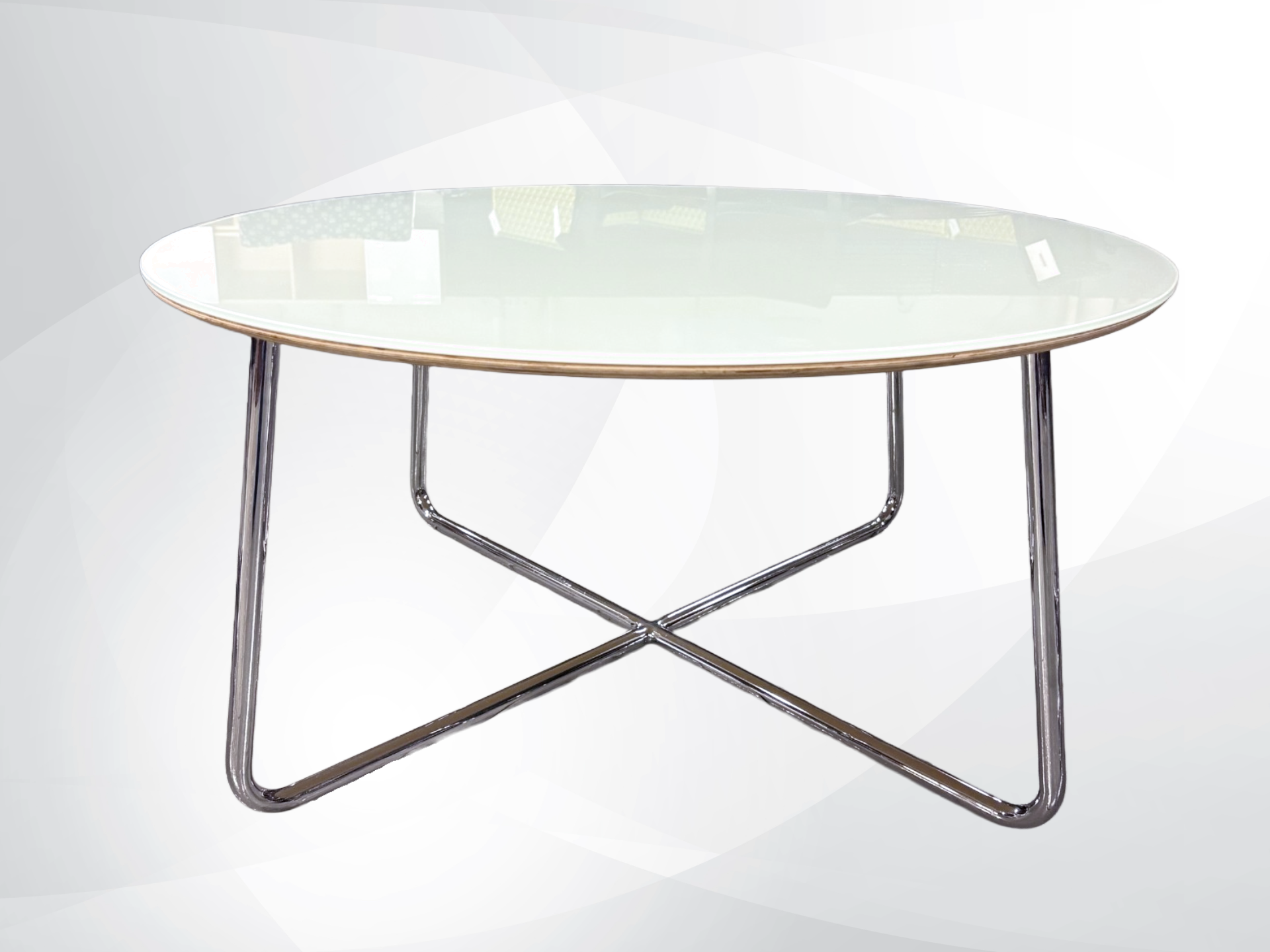 An Round coffee table with a clear glass top and a polished chrome metal base featuring an X-shaped leg design.