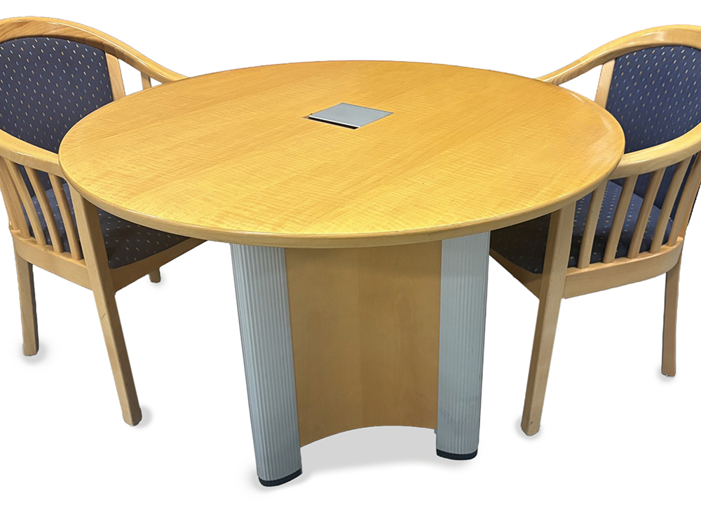 An oval wood conference table with a light oak finish and silver pedestal legs, shown with two matching wooden chairs featuring blue patterned upholstery in an office setting.
