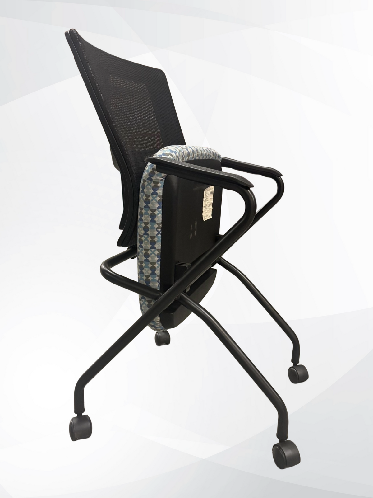 A black mesh office chair with a black metal frame and casters, featuring a patterned blue and gray lumbar support cushion, shown from a side angle on a light gray background.
