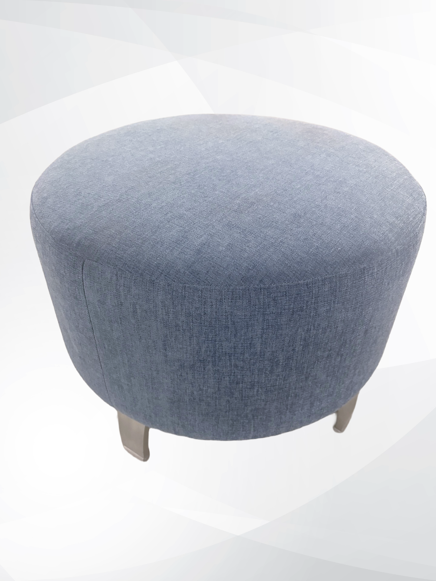 A round upholstered ottoman stool with a textured mutted blue fabric cushion and short metallic legs, shown on a light gray background.